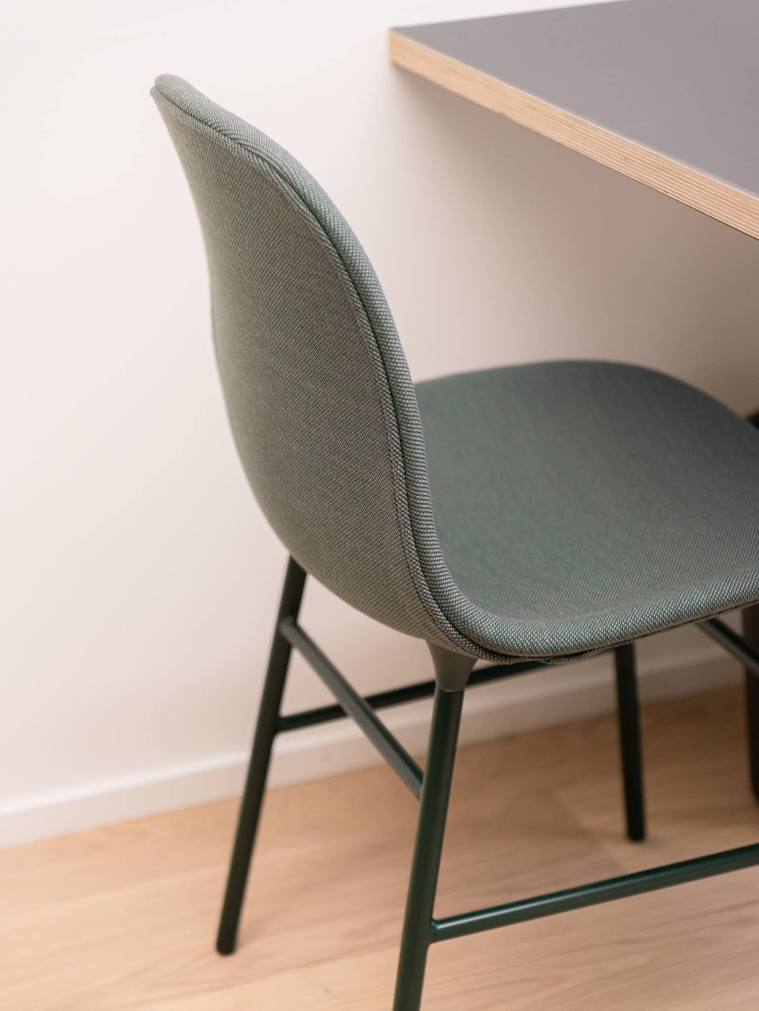 Detailaufnahme eines mit Stoff &uuml;berzogenen Stuhls, der an einem Tisch steht
